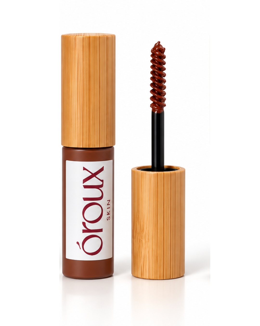 A bottle of oroux Skin auburn copper brow gel with bamboo-style packaging next to its applicator wand showing the brown gel on the brush, on a white background.