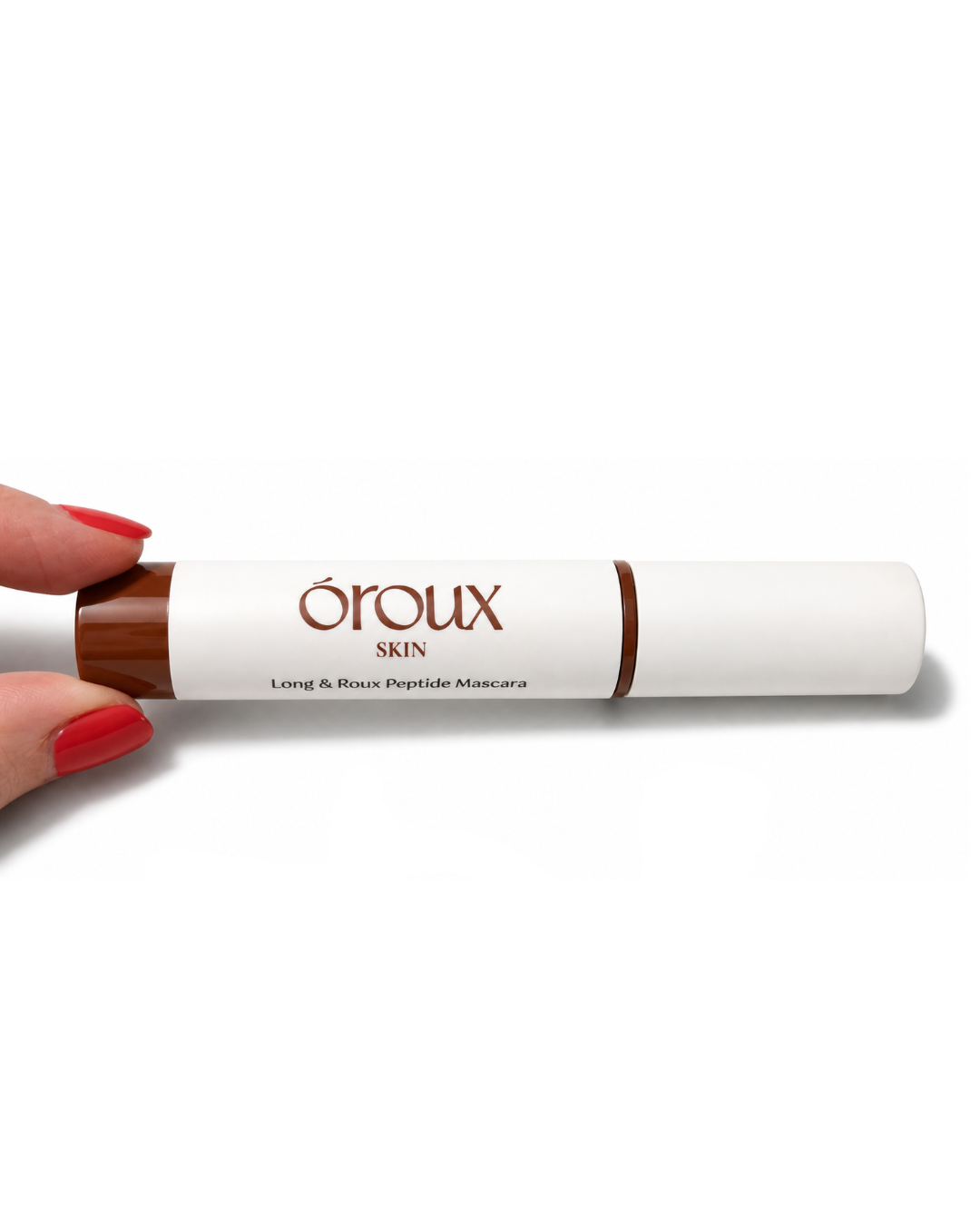 A hand with red painted nails holds a white tube of Éroux Skin Long & Rixou Peptide Mascara against a plain white background.