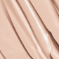 Close-up of a smooth, glossy beige cosmetic cream concealer by oroux skin or foundation swatch with diagonal ridges and soft highlights.