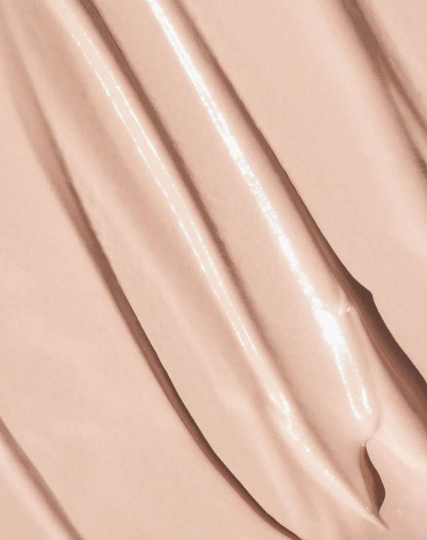 Close-up of a smooth, glossy beige cosmetic cream concealer by oroux skin or foundation swatch with diagonal ridges and soft highlights.