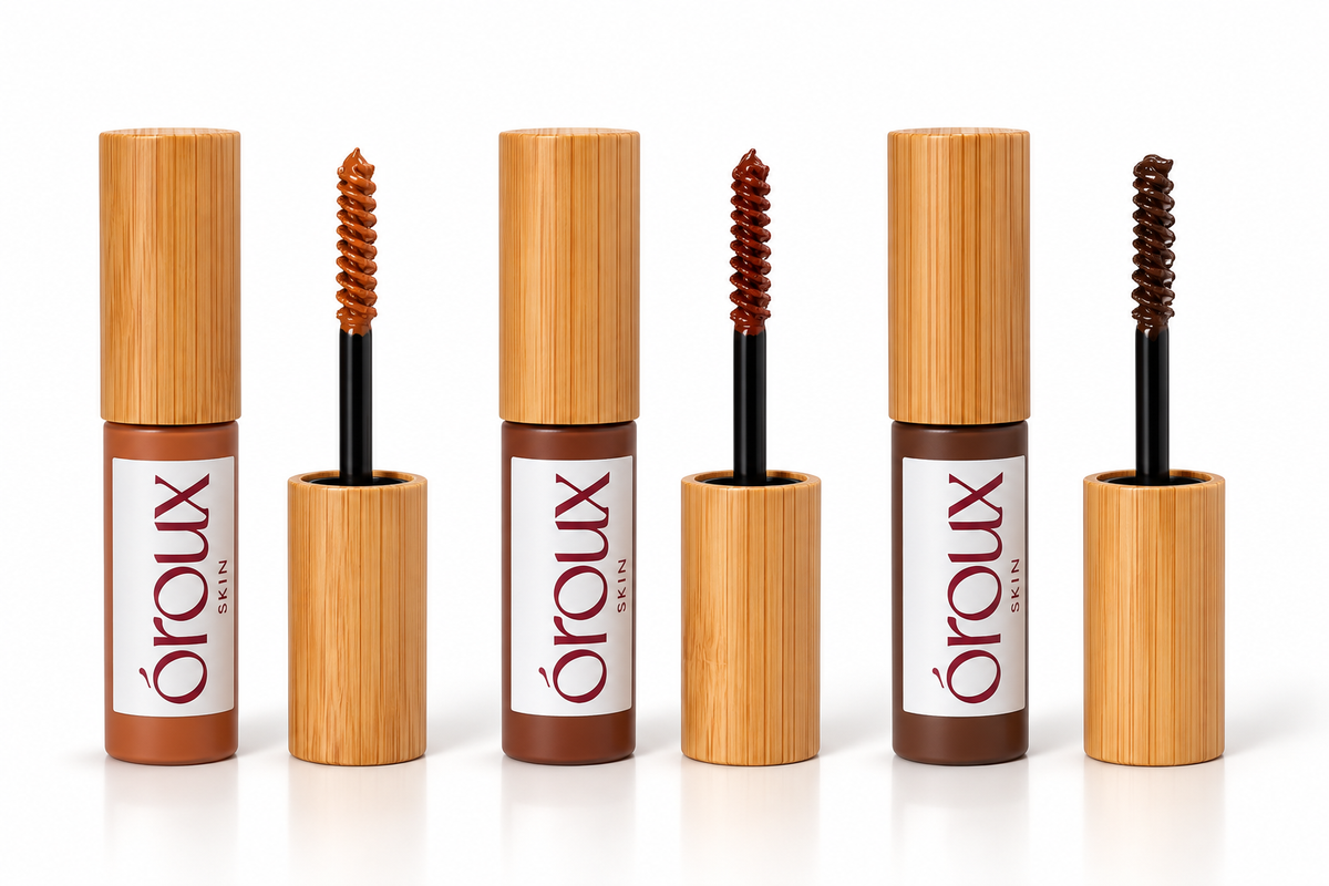 Five Oroux eyelash and brow products arranged in a row on a white background, with two closed tubes showing their bamboo-textured caps and two open tubes showing the spoolie and brush applicators.