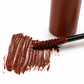 A close-up of a copper red cosmetic product swatch with a thick textured smear, a wand applicator coated with the product, and part of the brown bottle on a clean white background. for redheads and gingers