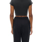 Person wearing a black crop top and black pants on a white background showing back of shirt