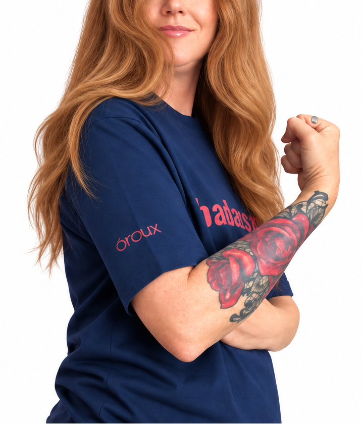 A split-screen lifestyle image of a woman with long red hair modeling a navy blue t-shirt. The left side shows her from the waist up with her hand on her hip, and the right side shows a closer cropped view of her flexing her arm.