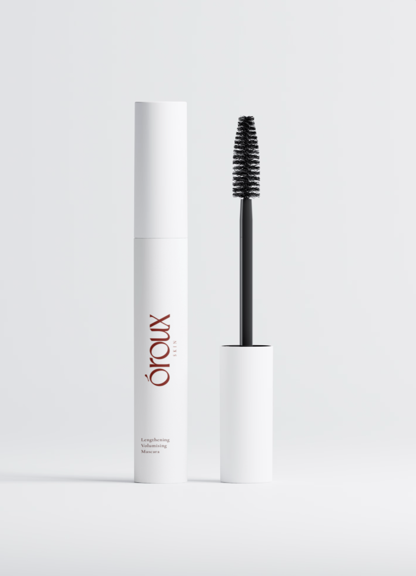 A white cosmetic tube labeled óroux with the wand removed and standing beside it on a clean light gray studio background.