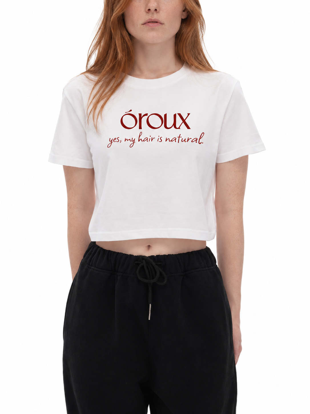 A model wearing a white cropped t-shirt with red text that reads 'oroux yes, my hair is natural.' and black sweatpants, shot against a plain white background.