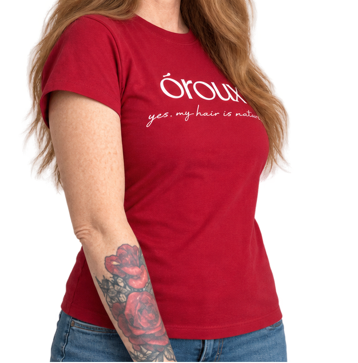 A side-by-side comparison of a woman modeling a red short-sleeve t-shirt with white printed text that reads 'óroulx yes my hair is natural'. The left side shows the front view with her hand on her hip, and the right side shows the side profile view.